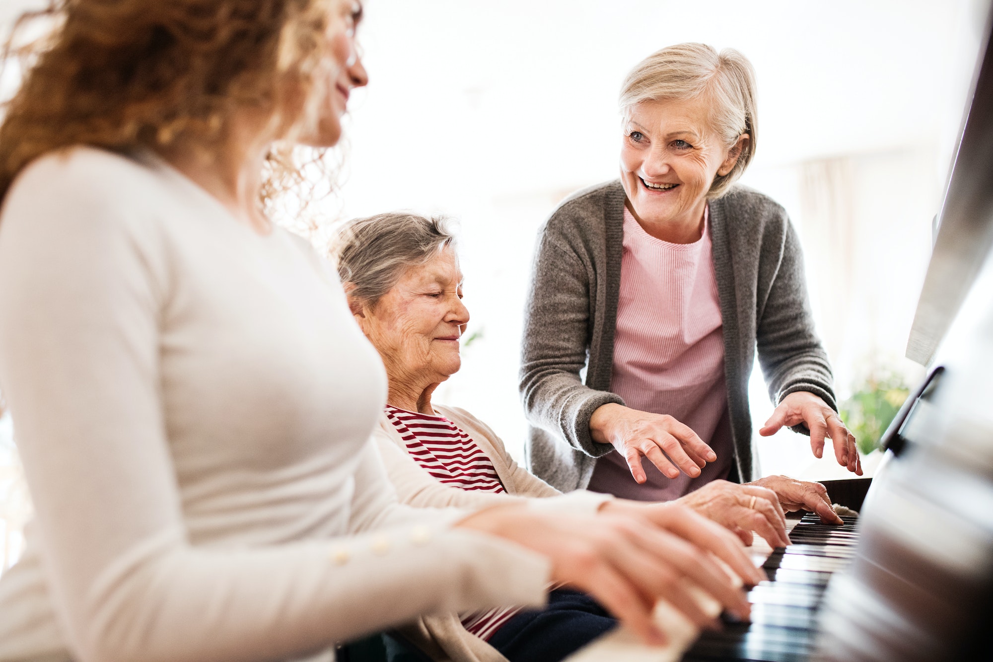 A girl with mother and grandmother playing the piano.